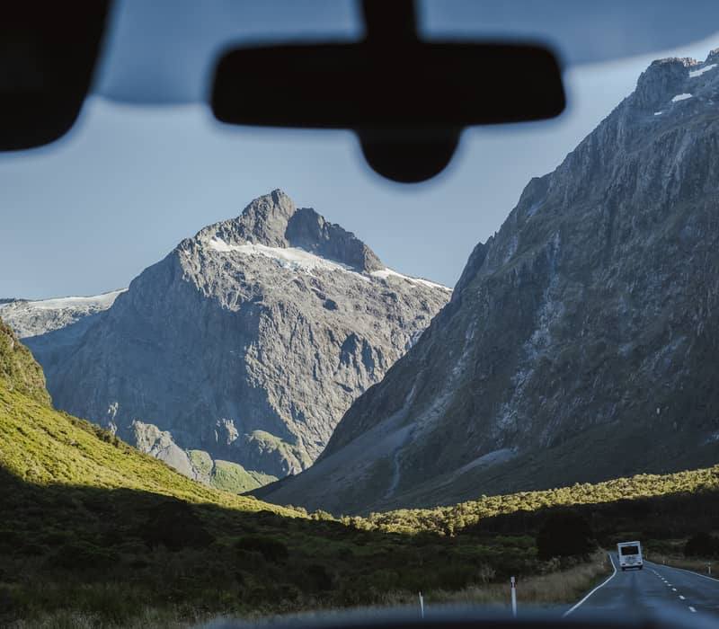 View of mountains and valley through front windshield of a van on a sunny day